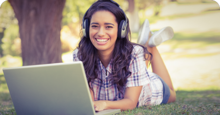 Student smiling outdoors with laptop